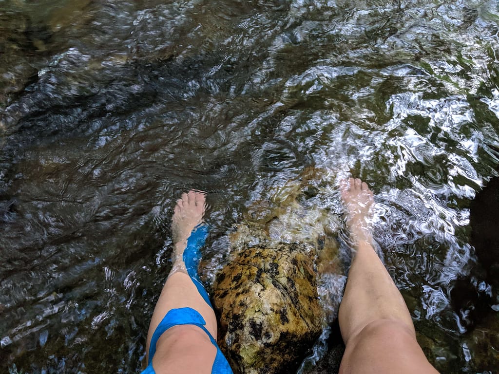 Legs covered in KT Tape in a body of water- KT tape is something I never leave out of my Hiking First Aid Kit