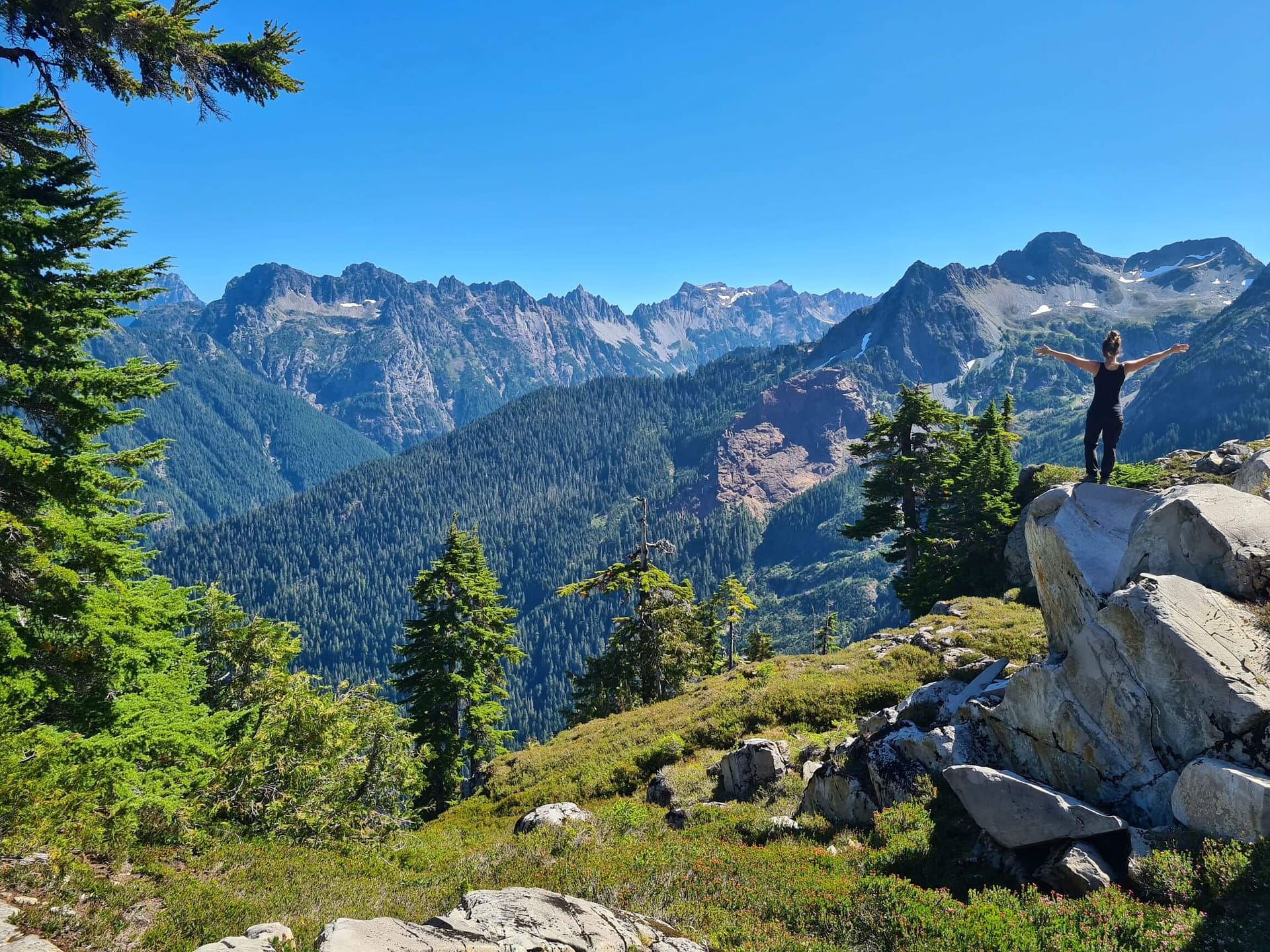 a girl with her arms out, back facing the camera looking at a mountain range around Gothic Basin